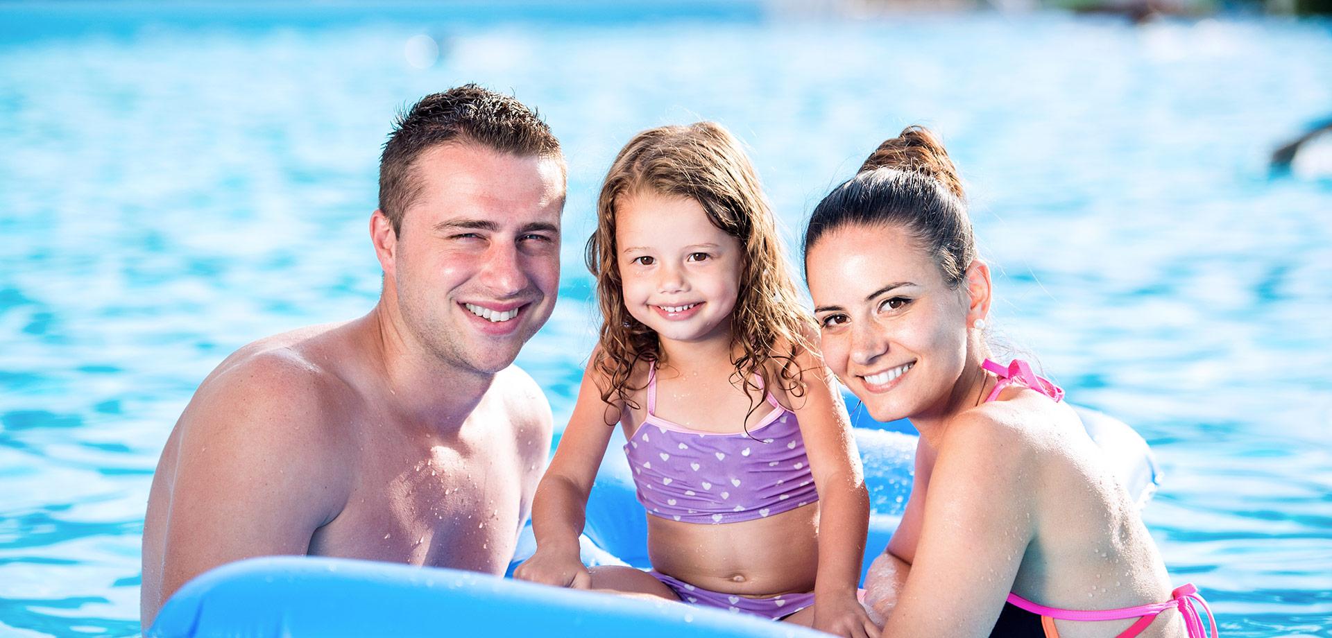 Famiglia sorridente in piscina, godendo una giornata di sole e relax sull'acqua.