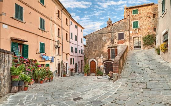 Piazza pittoresca con case colorate e fiori, tipica di un borgo italiano.