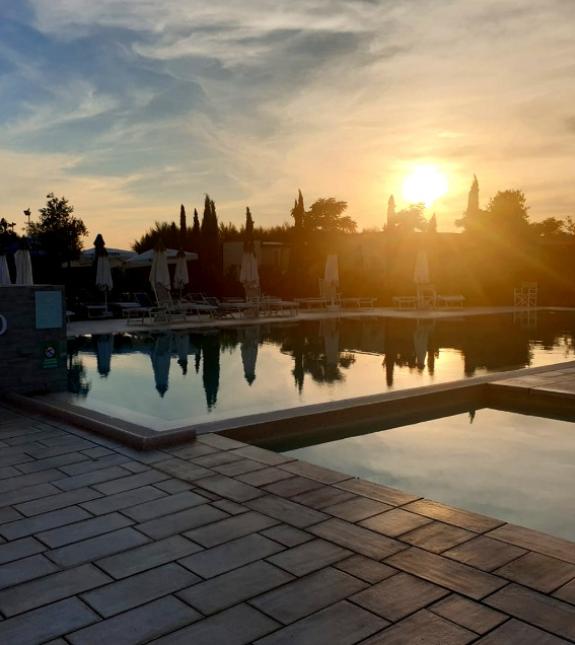 Piscina al tramonto con ombrelloni chiusi e cielo sereno.