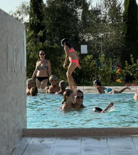 Persone si rilassano in piscina, godendo del sole e dell'acqua.