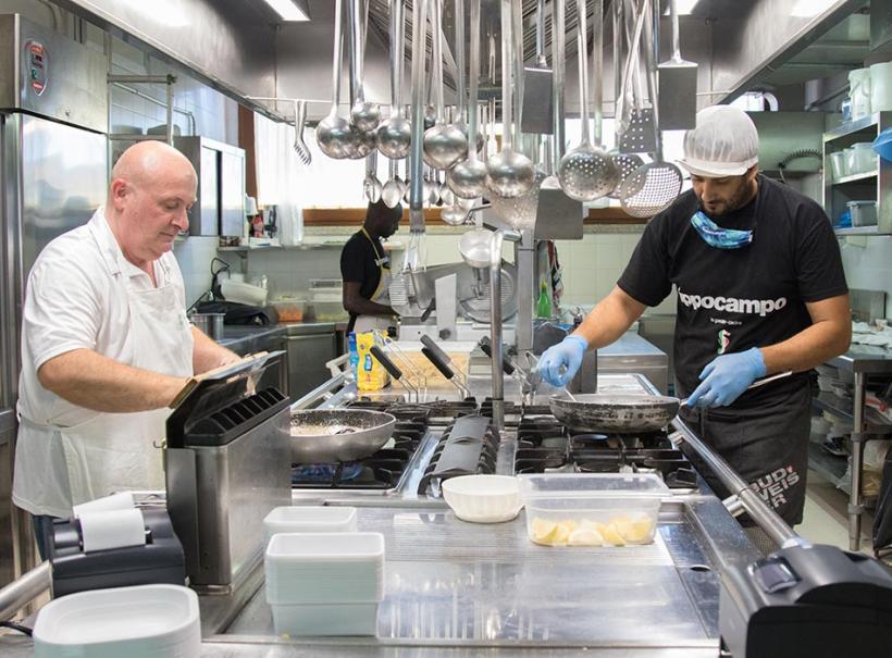 Chef al lavoro in una cucina professionale, preparano piatti con attenzione e precisione.