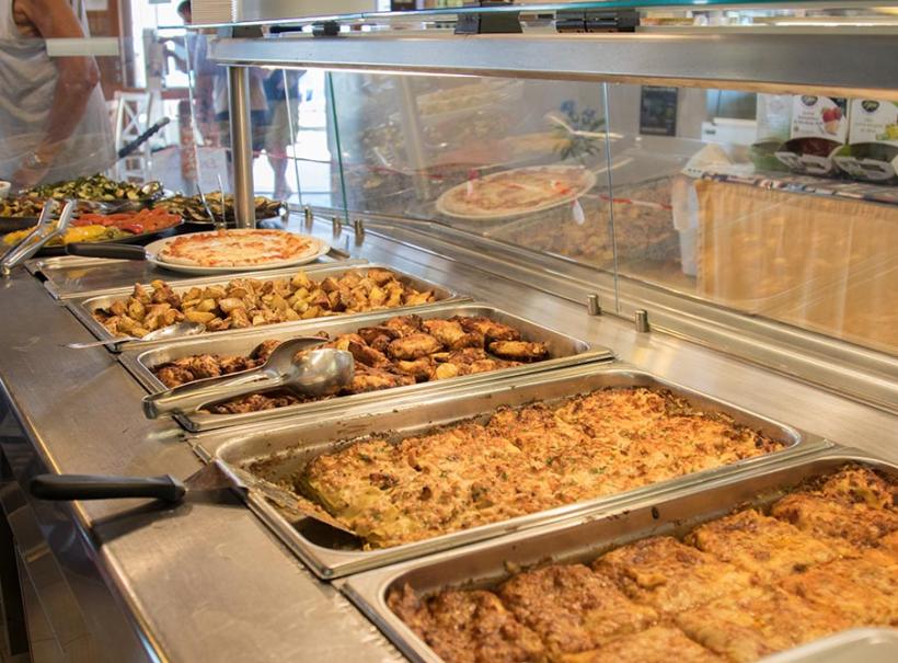 Buffet con piatti caldi: lasagne, patate arrosto, pollo e verdure grigliate.