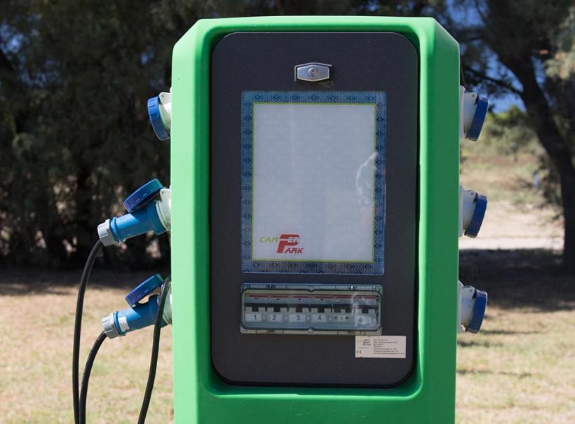 Colonnina verde per la ricarica elettrica con prese blu e schermo frontale.