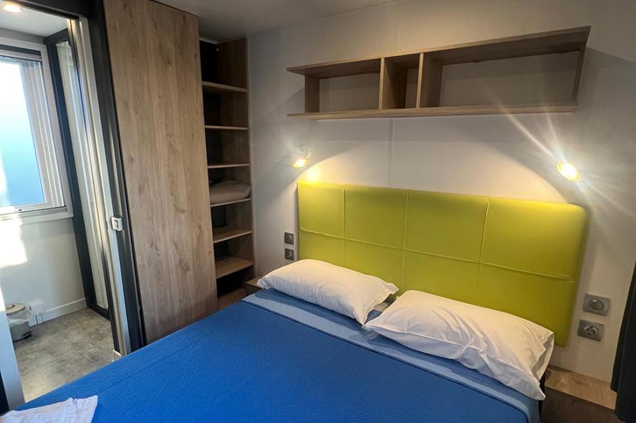 Camera da letto moderna con letto matrimoniale, testiera verde e copriletto blu.